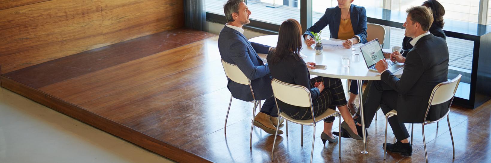 Group of university administrators and law enforcement personnel discussing campus emergency planning at a conference room table