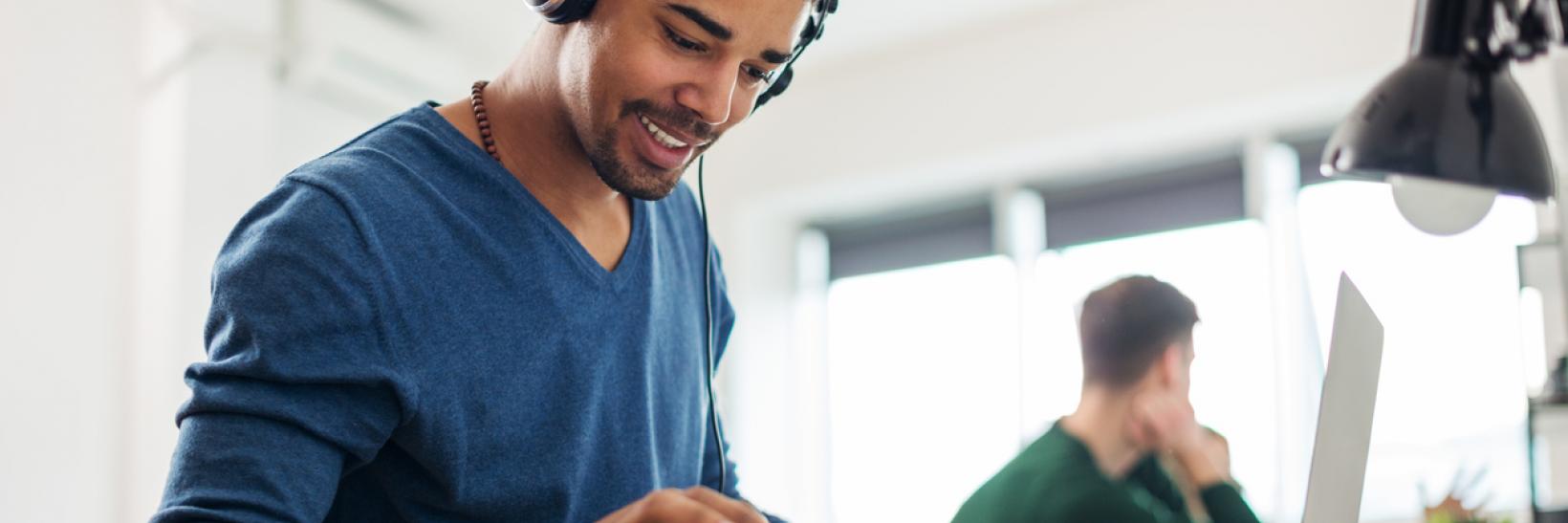 A man wears headphones and listens to the Winter 2017 SEVP InFocus Webinar