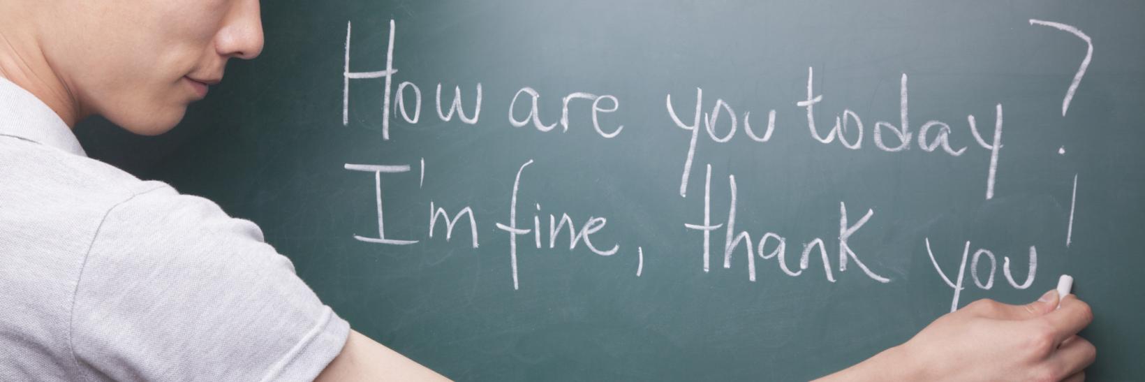 man writes English sentences on chalkboard