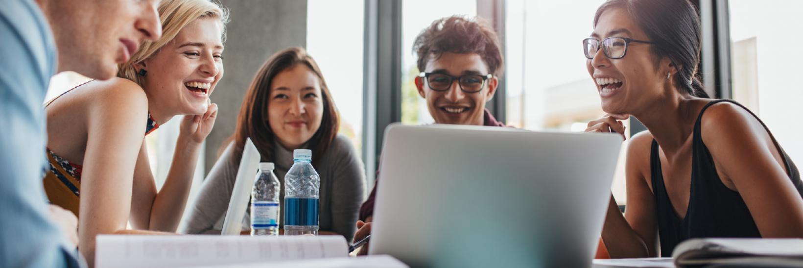 A group of international students look at the Guide to Studying in the States on a laptop