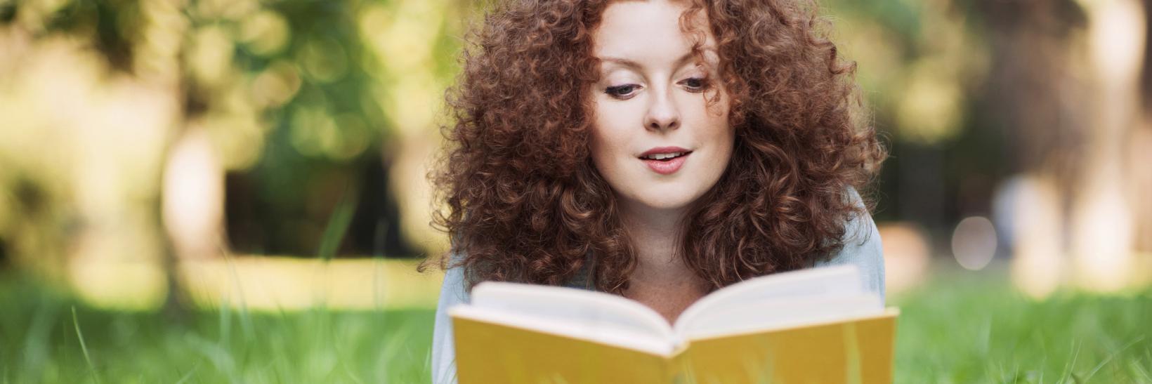 girl reads a book in a field