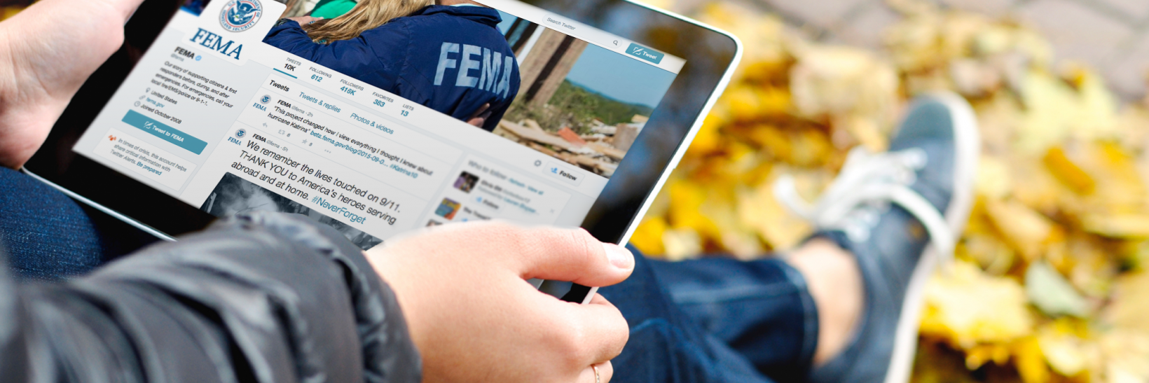 Student holding an ipad with FEMA's twitter account on screen