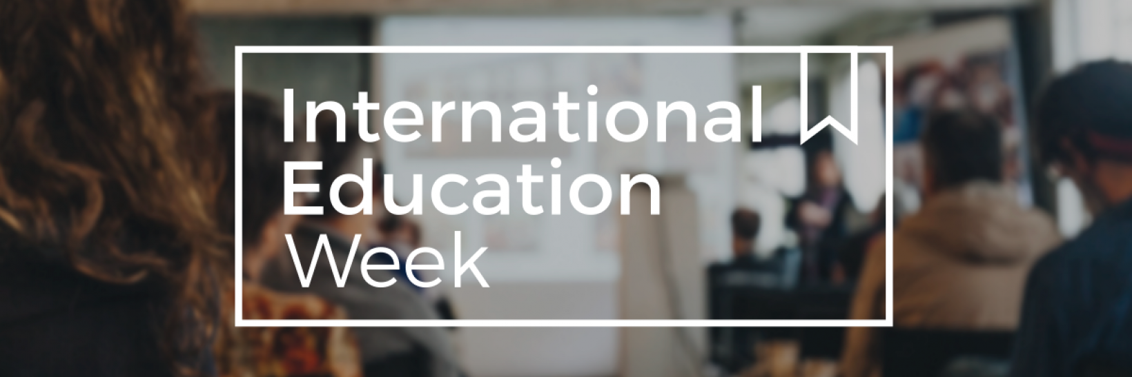 An classroom full of people looking at a projector while an instructor speaks with the words International Education Week across the image