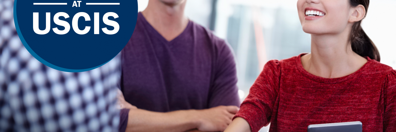 Woman shaking hands with coworker with a man smiling, looking on in the background