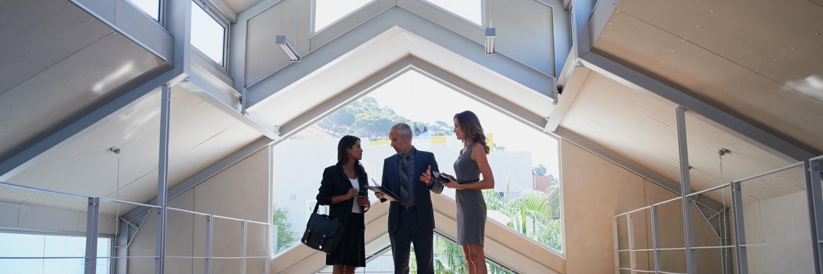 Three business people talking in a hallway.