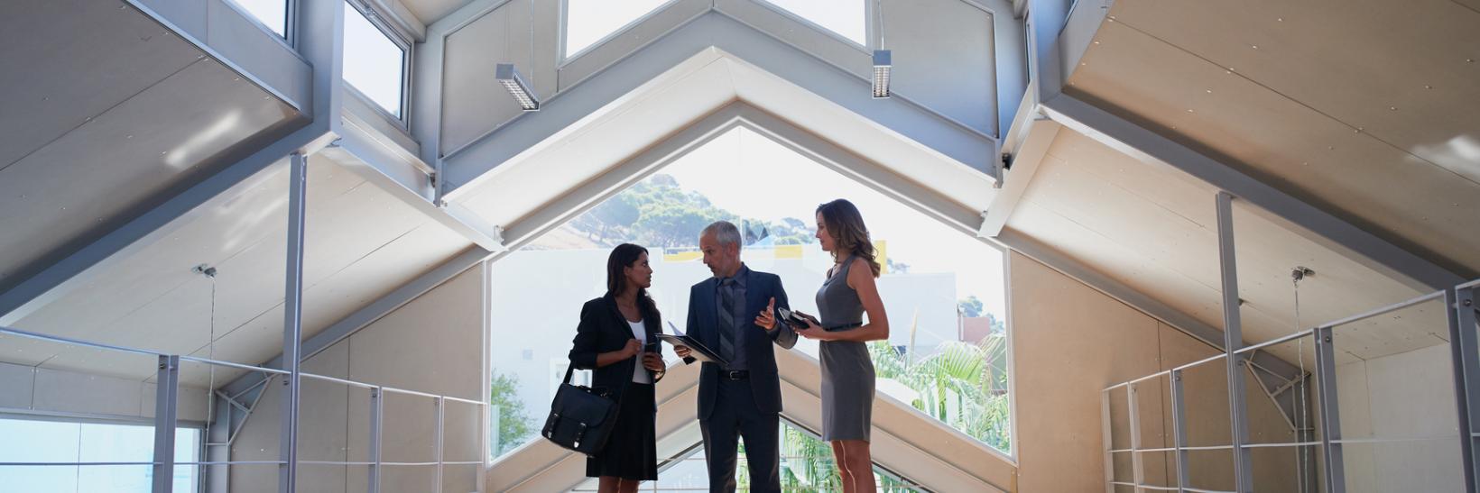 Three business people talking in a hallway. 