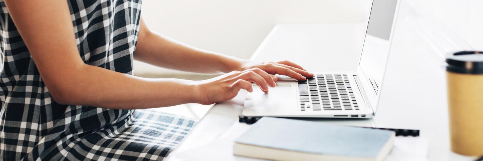 A student sitting at a table working on her laptop