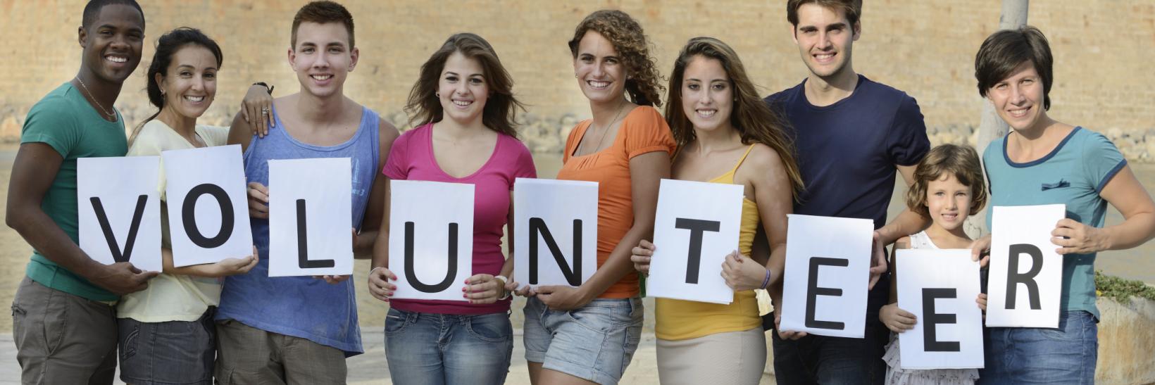 group of young adults holding a volunteer sign