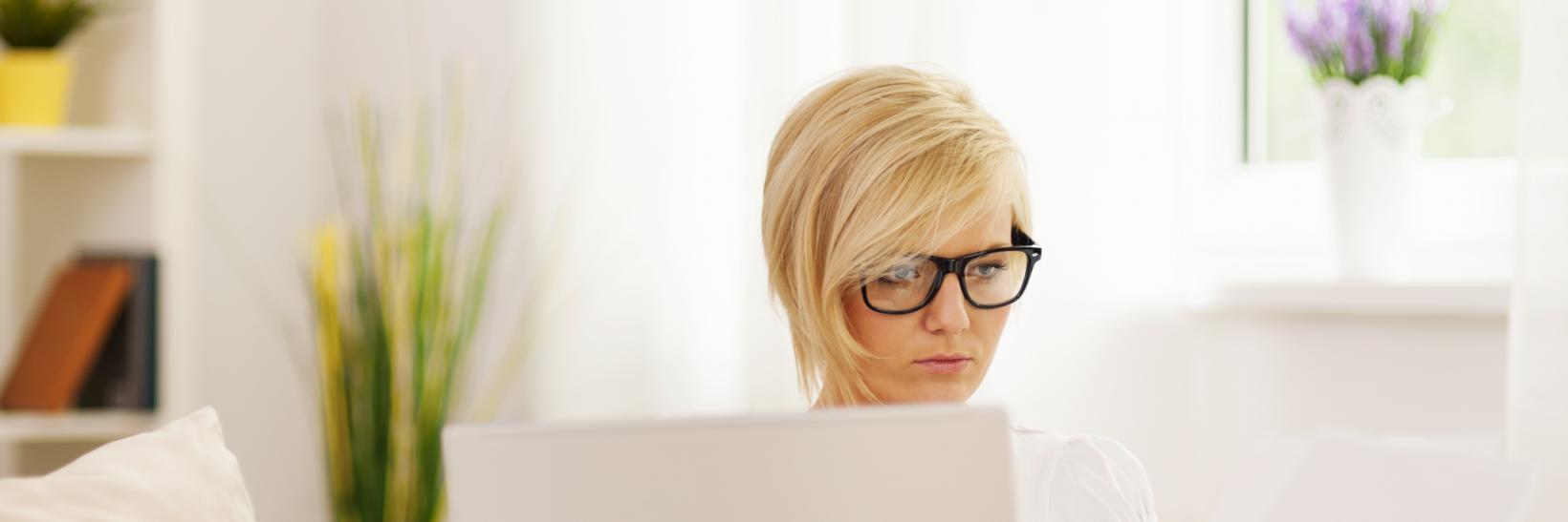 woman reads a form while on a laptop