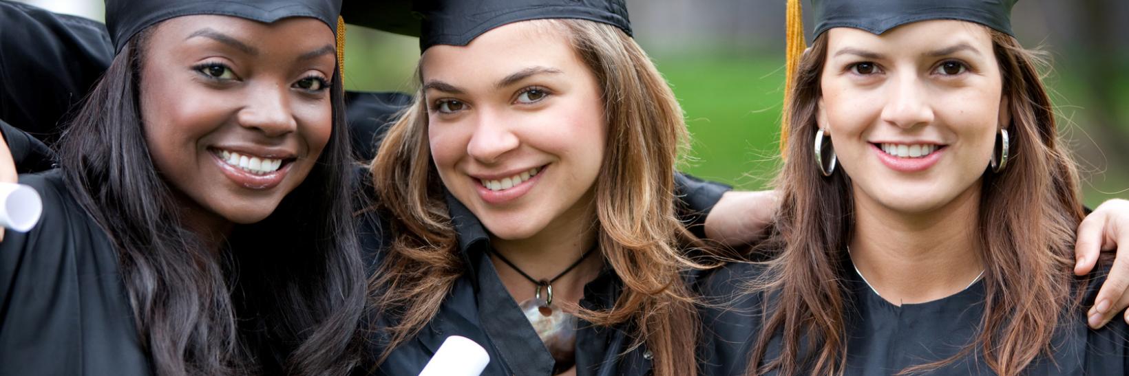 Female students wearing caps and gowns at graduation.