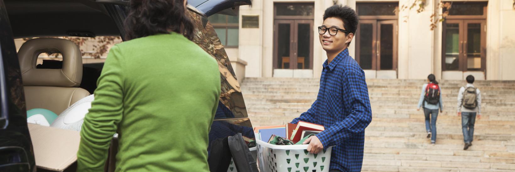 A Young man moving into a dormitory on a college campus.