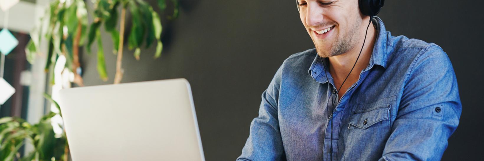 A man listening to headphones on his laptop computer.