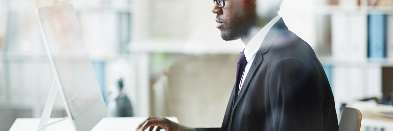 man sitting at a desk, working on his computer