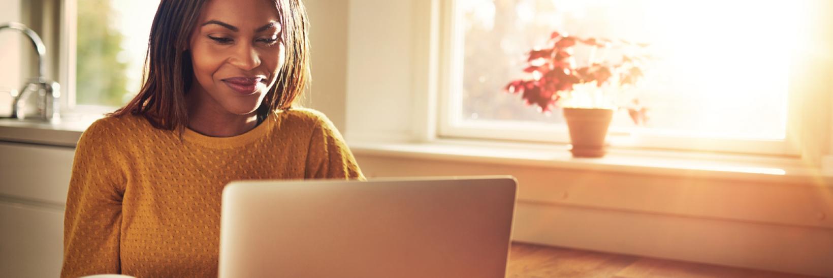 A woman drinking a coffee looking at her laptop computer.