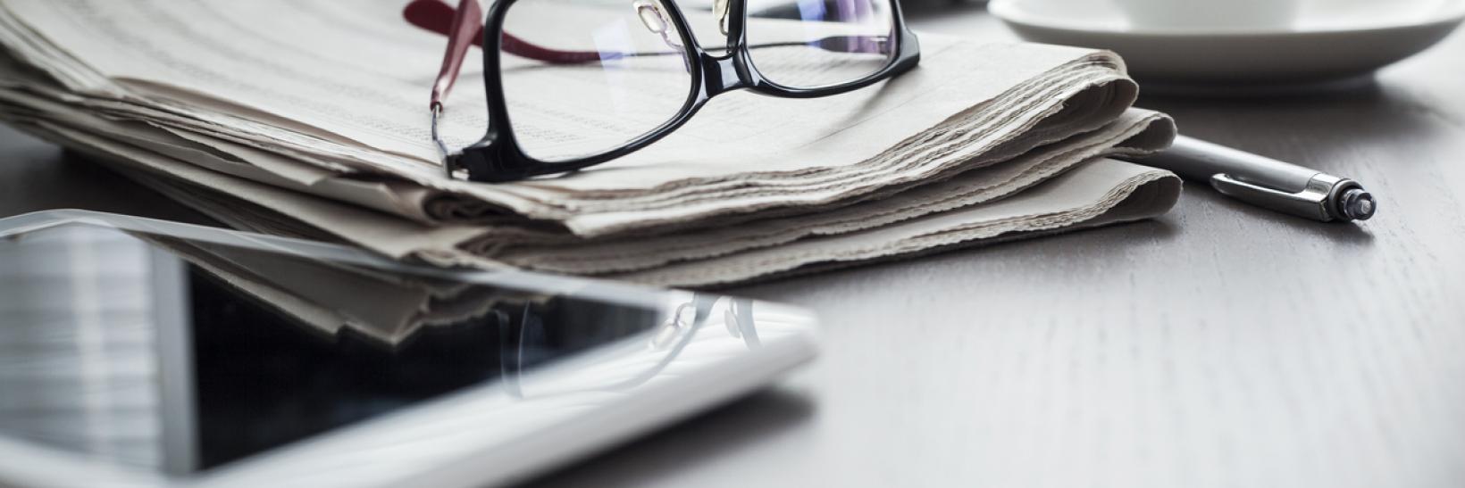 A pair of glasses on top of a stack of paper.