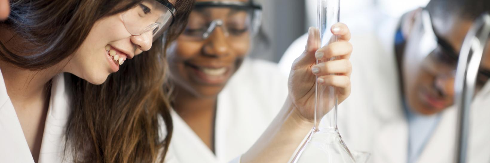 Young student looking at a chemistry beaker. 