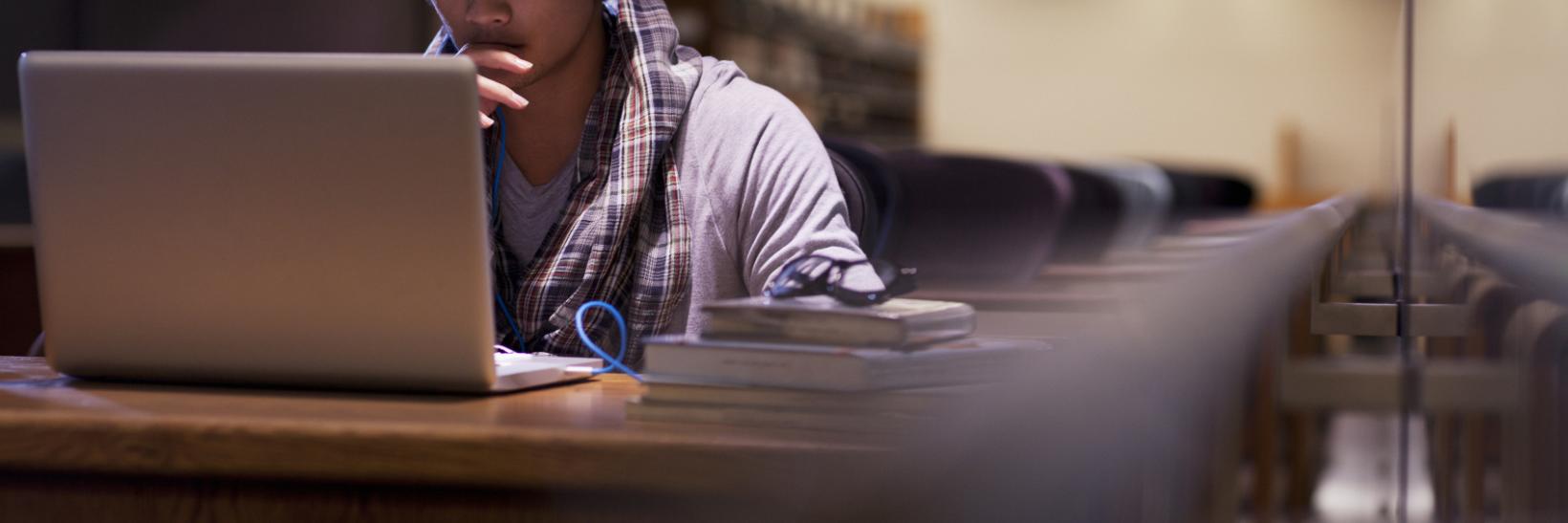 Student working on laptop in a library. Student working on laptop in a library.