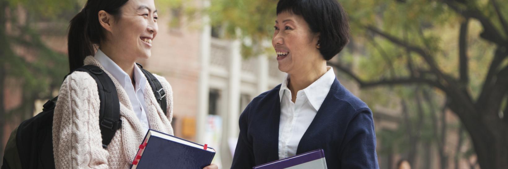 teacher and student talk outside on campus