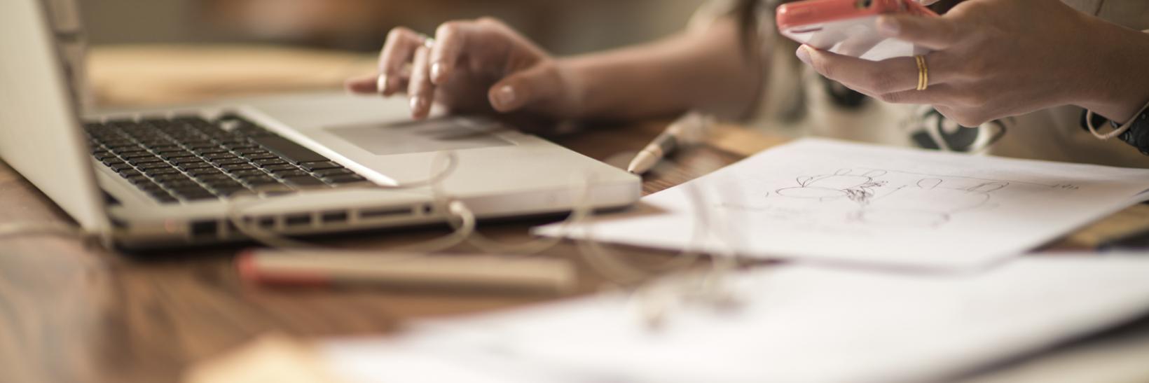 woman working on a laptop and cell phone