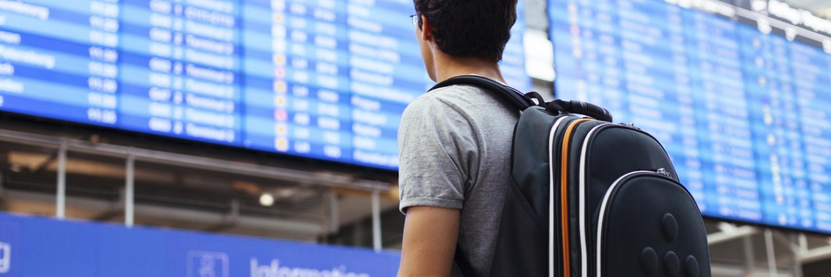 male traveler looking at airport flight schedule