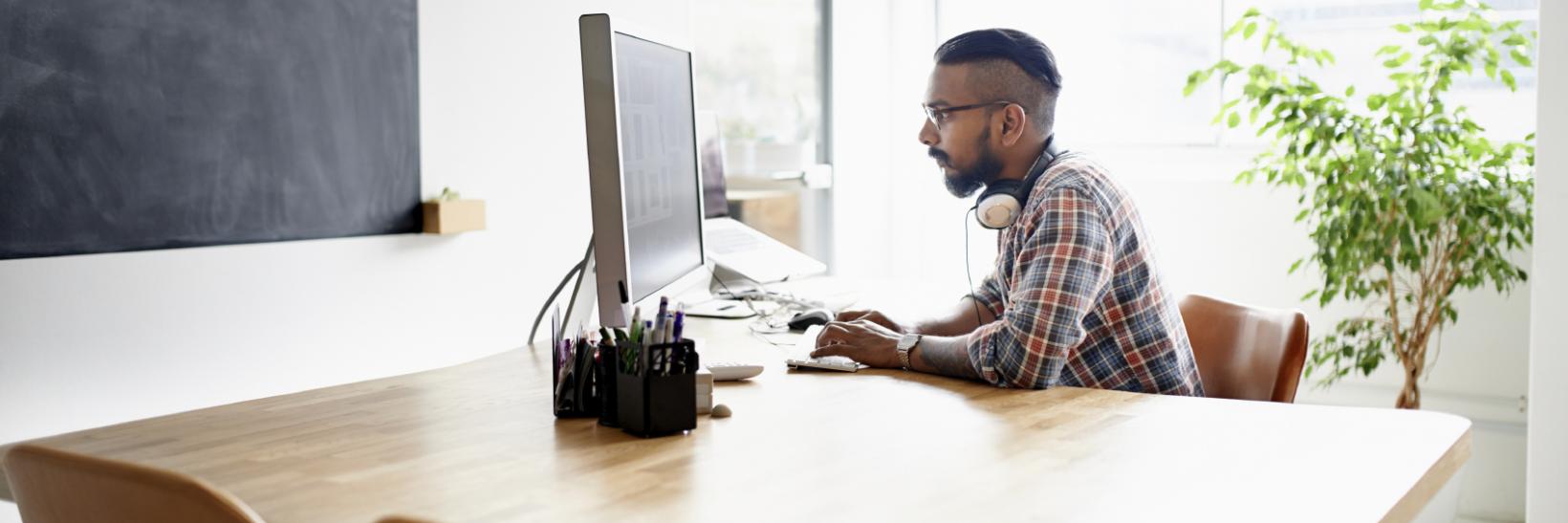 man sitting at clean wooden desk on a computer