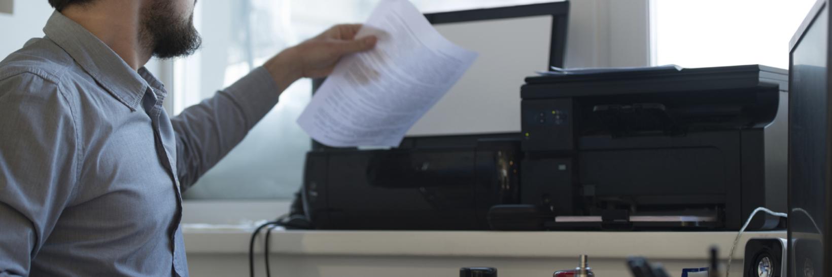 Man sitting at a desk, scanning a piece of paper
