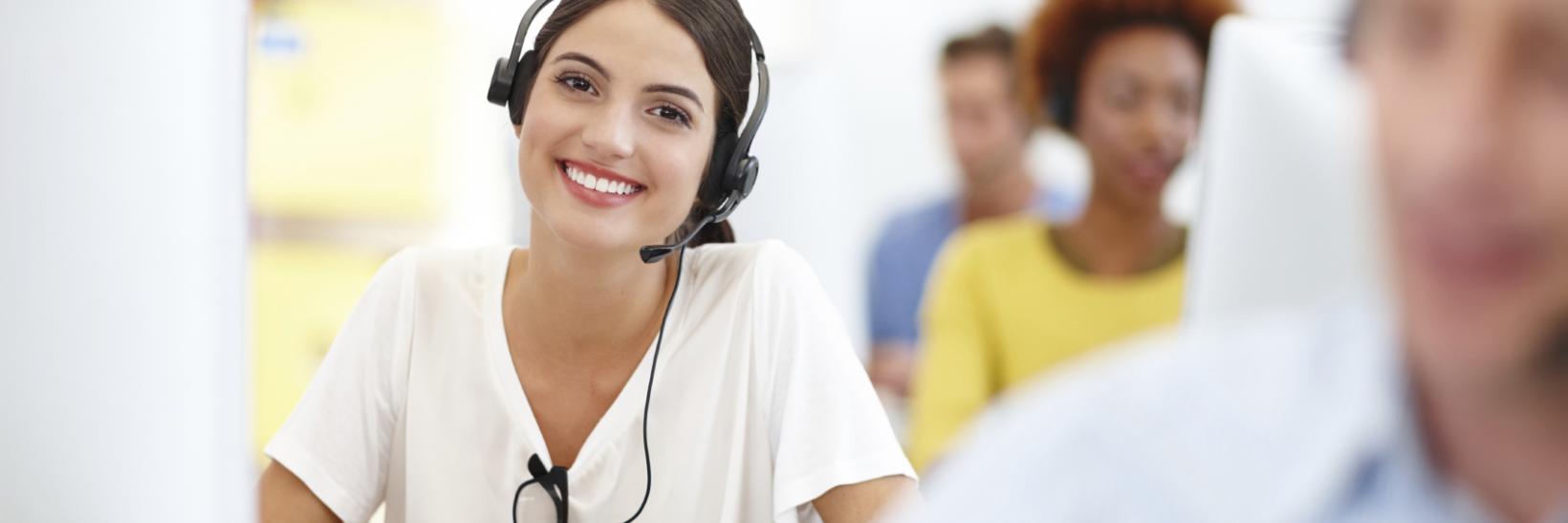 Smiling woman working at a computer in a call center.