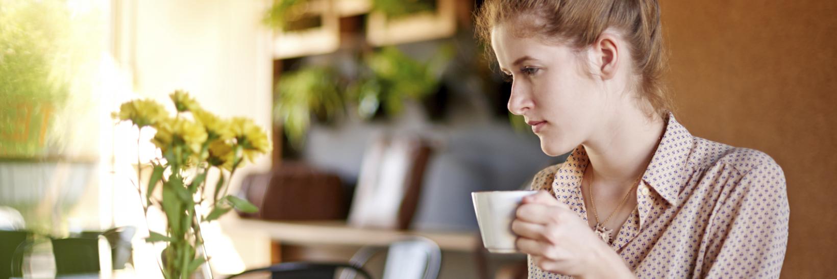 Woman drinking coffee working on a laptop 