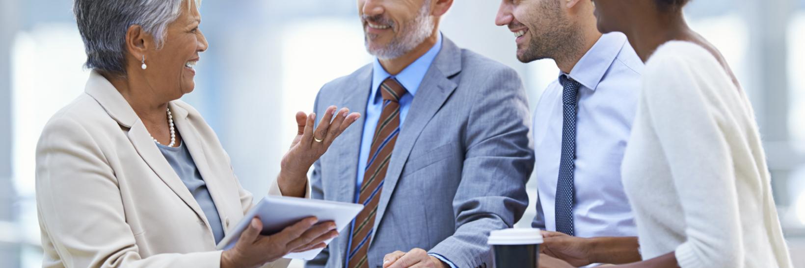Group of professionals talking around a standing table.