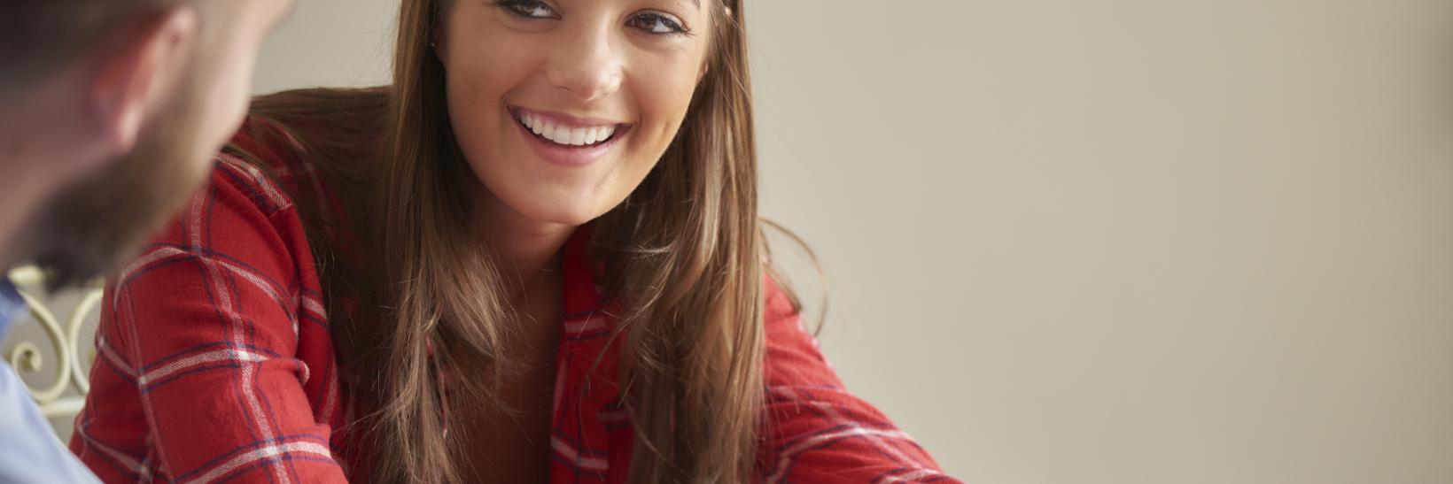 A young female student smiling and talking with a school adviser.