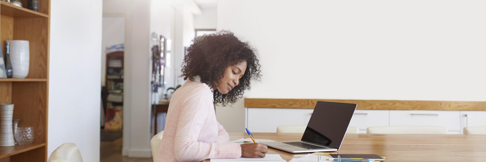 Woman working at a table, with her laptop open. 