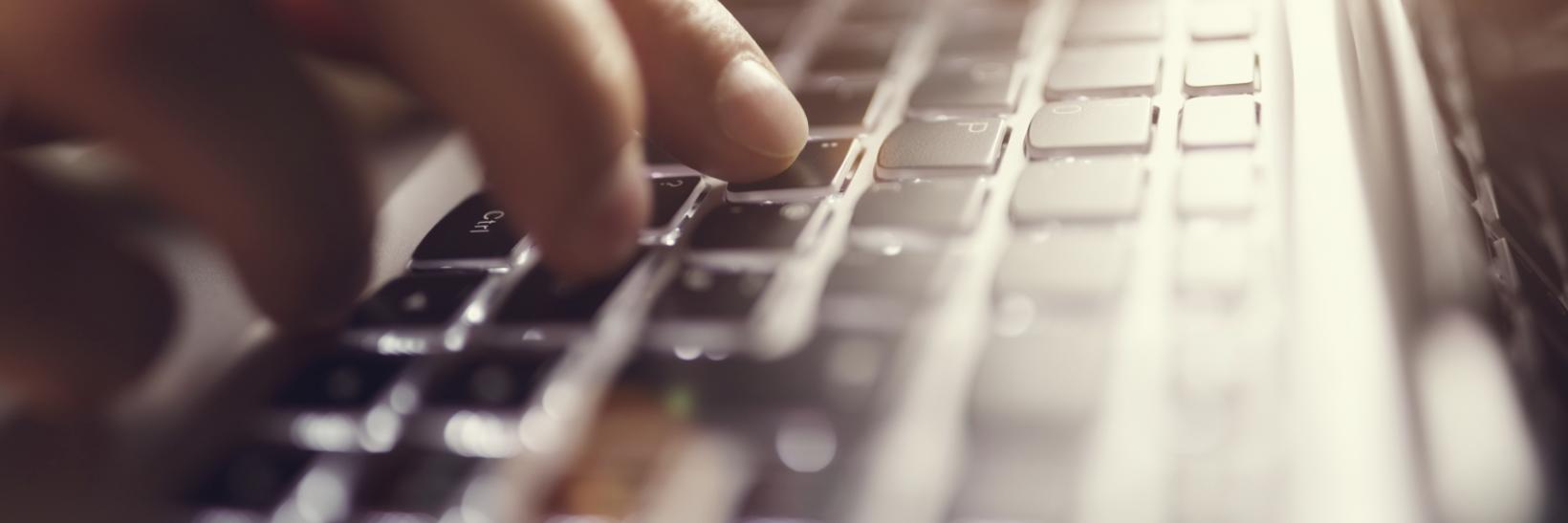 Hands typing on an illuminated keyboard