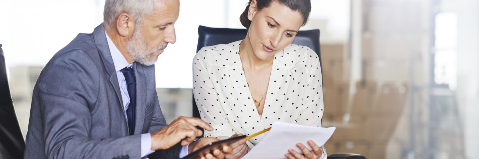 Two people reading a document. 