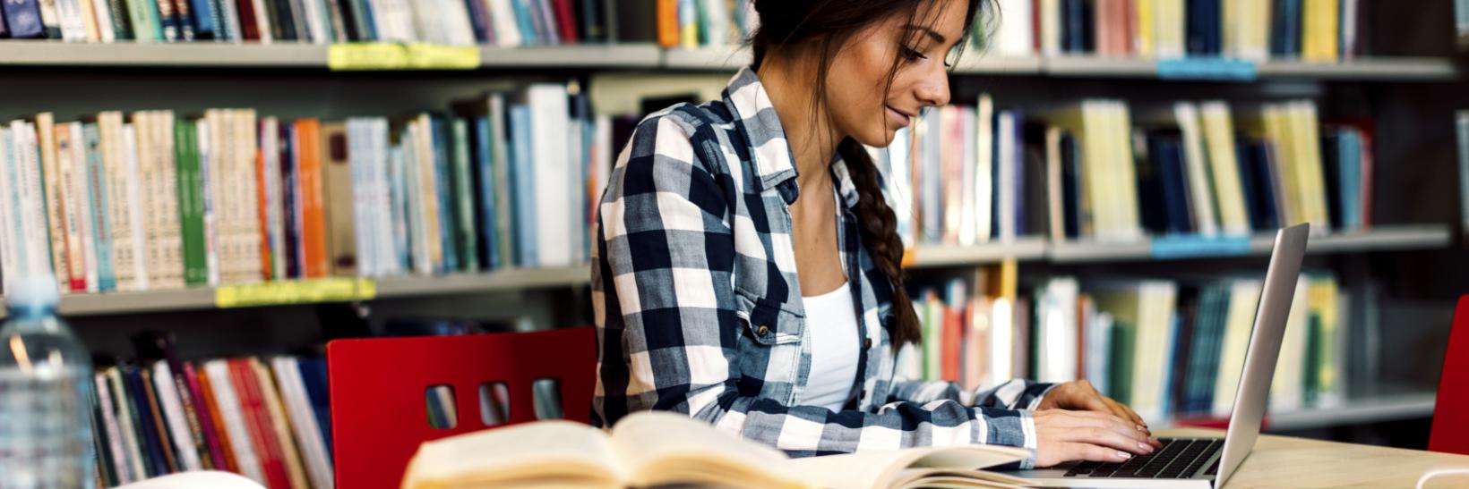 Woman using laptop in a library.