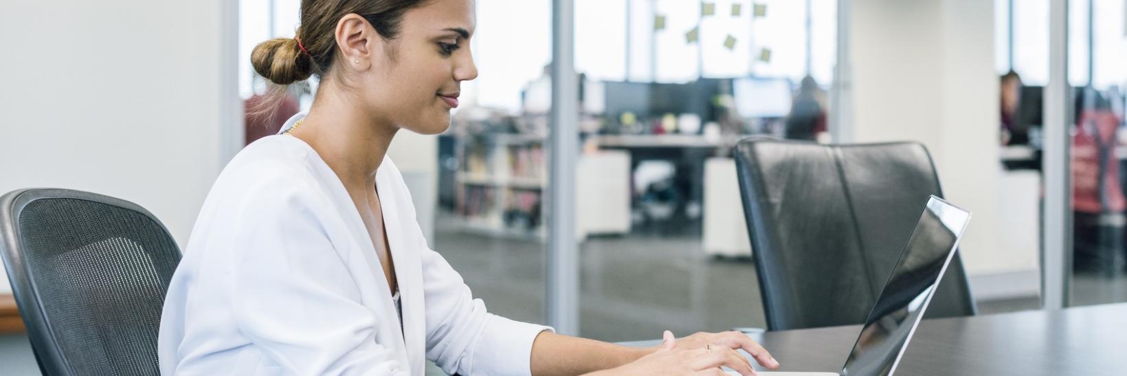 A woman working on her laptop computer in an office.