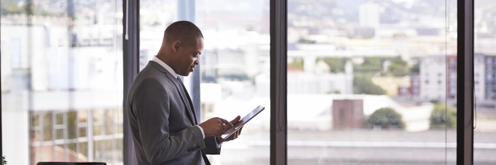 A man looking at a tablet device in a office. 