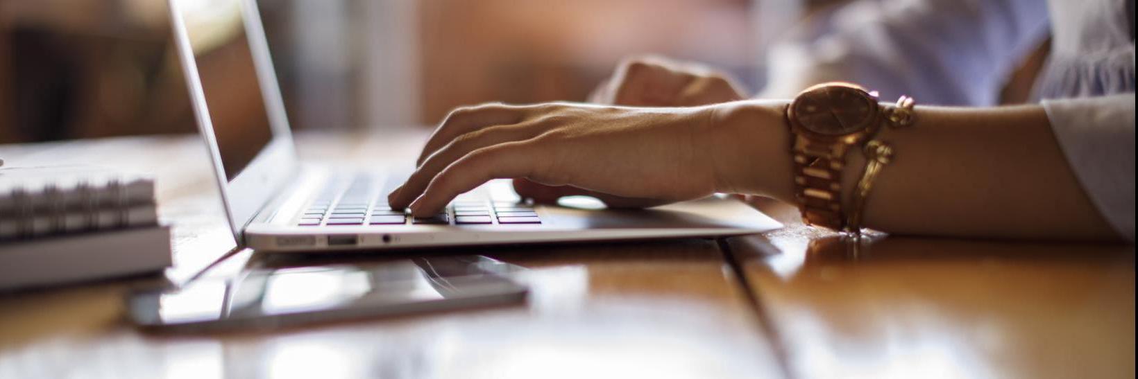 Hands typing on a laptop