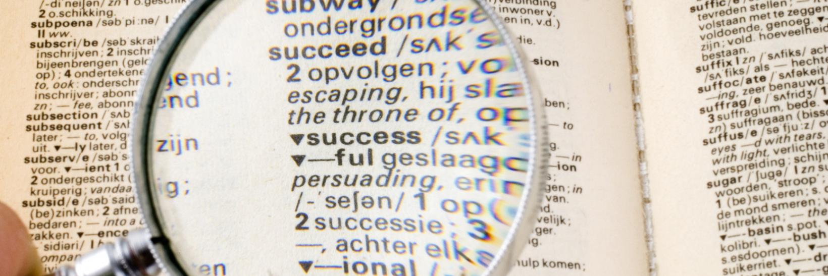 Person examines dictionary with looking glass. 