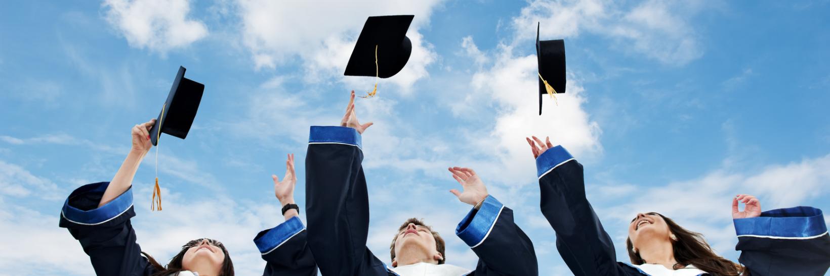 Three graduates throw their caps. 