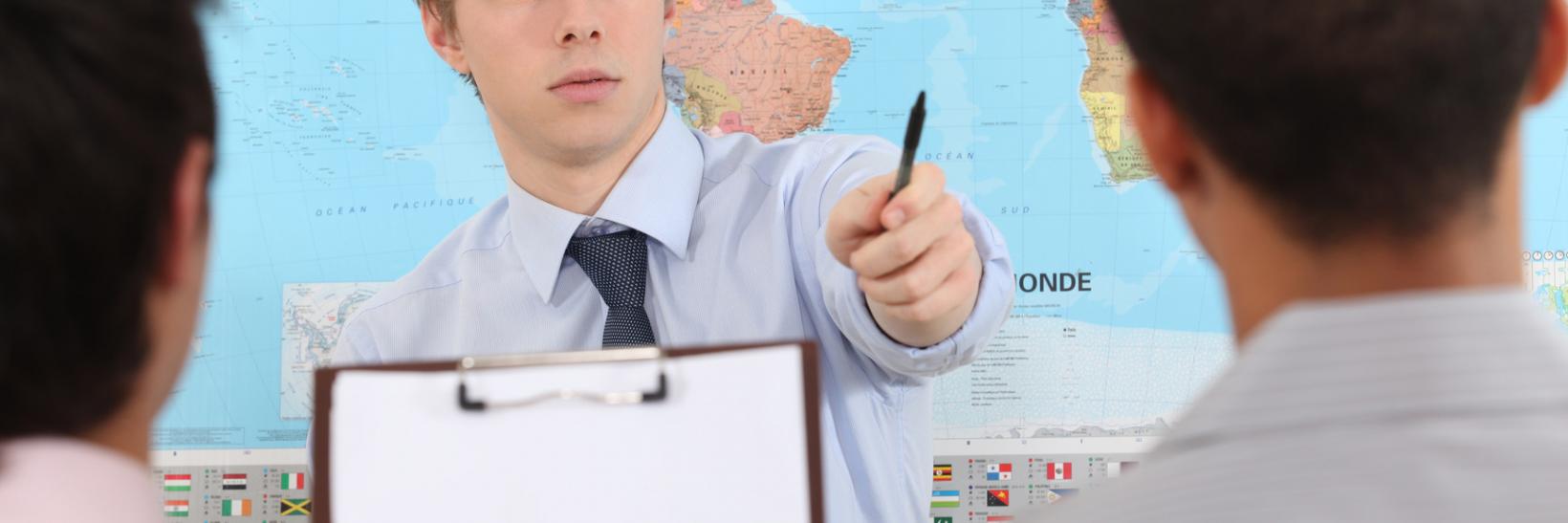 Man stands in front of map in classroom. 