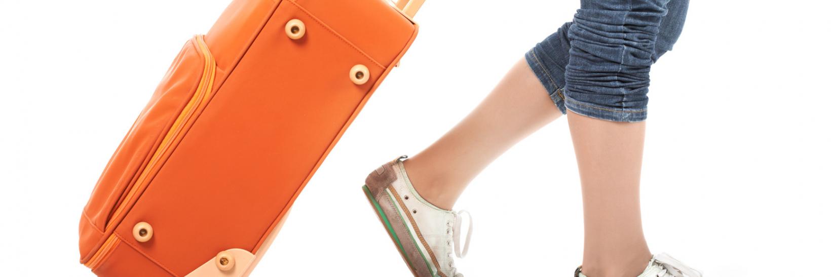 Girl walking with orange suitcase.