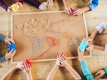 Aerial view of a group of young students working on an art project with yarn