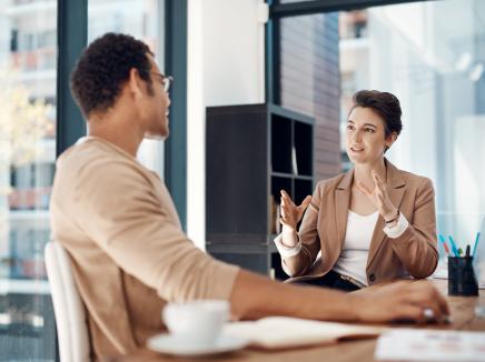 An SEVP field representative sits in an office with a designated school official and discusses SEVP regulations