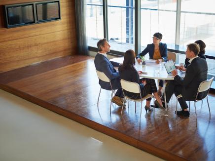 Group of university administrators and law enforcement personnel discussing campus emergency planning at a conference room table