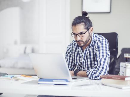 Man watching the SEVP InFocus Webinar on a laptop while sitting at a desk