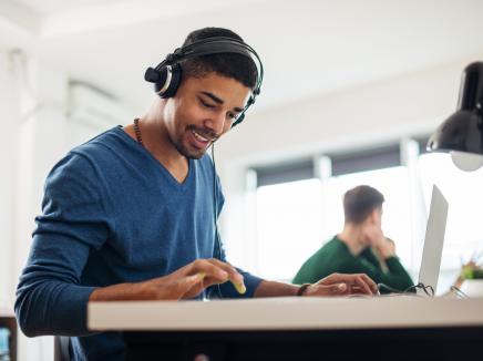 A man wears headphones and listens to the Winter 2017 SEVP InFocus Webinar