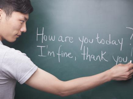 man writes English sentences on chalkboard