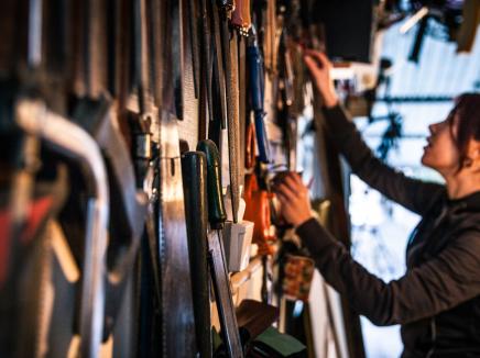 A female M-1 international student rummages takes tools off the wall of a garage