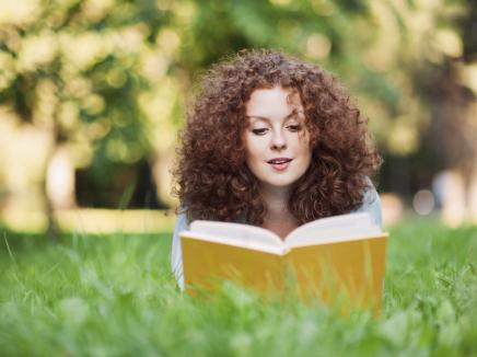 girl reads a book in a field