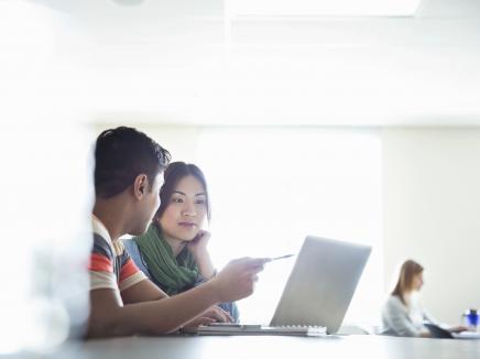 Students using laptops in classroom at college campus